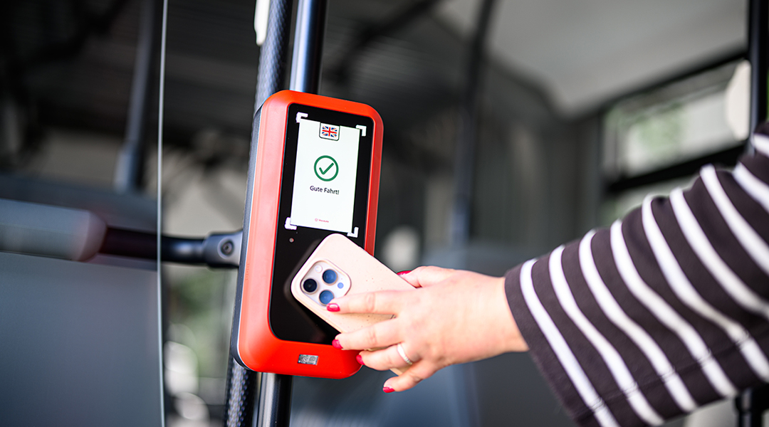 Eine Person hält ein Mobiltelefon vor ein Lesegerät.