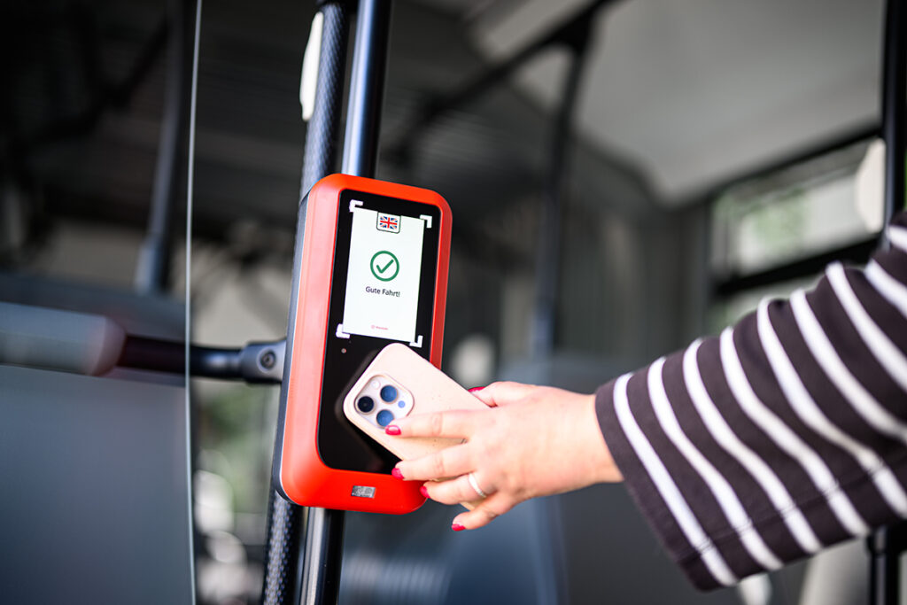 Eine Person hält ein Mobiltelefon vor ein Lesegerät.