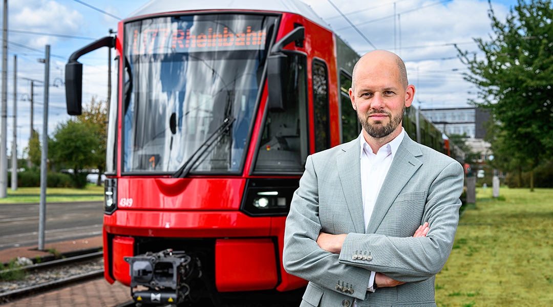 Eine Person steht vor einer Straßenbahn.