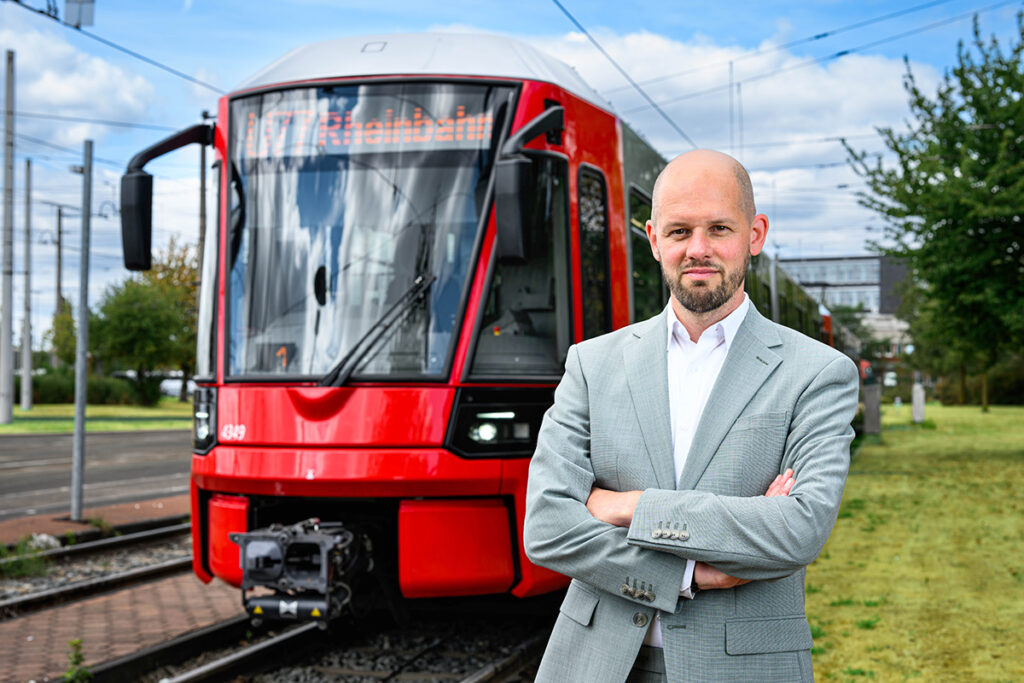 Eine Person steht vor einer Straßenbahn.