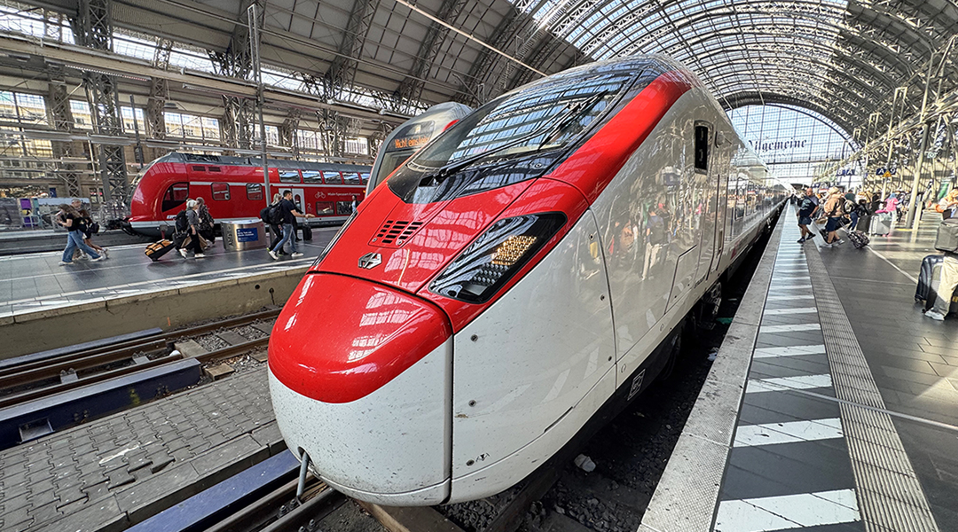 Ein Zug steht an einem Bahnsteig in einer Bahnhofshalle.