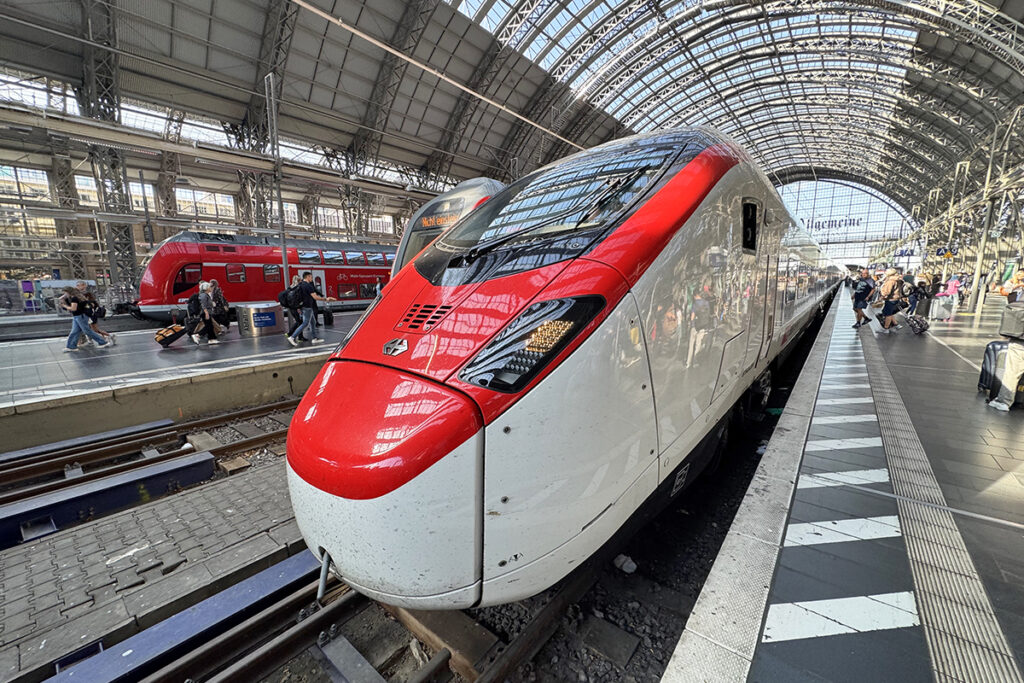 Ein Zug steht an einem Bahnsteig in einer Bahnhofshalle.