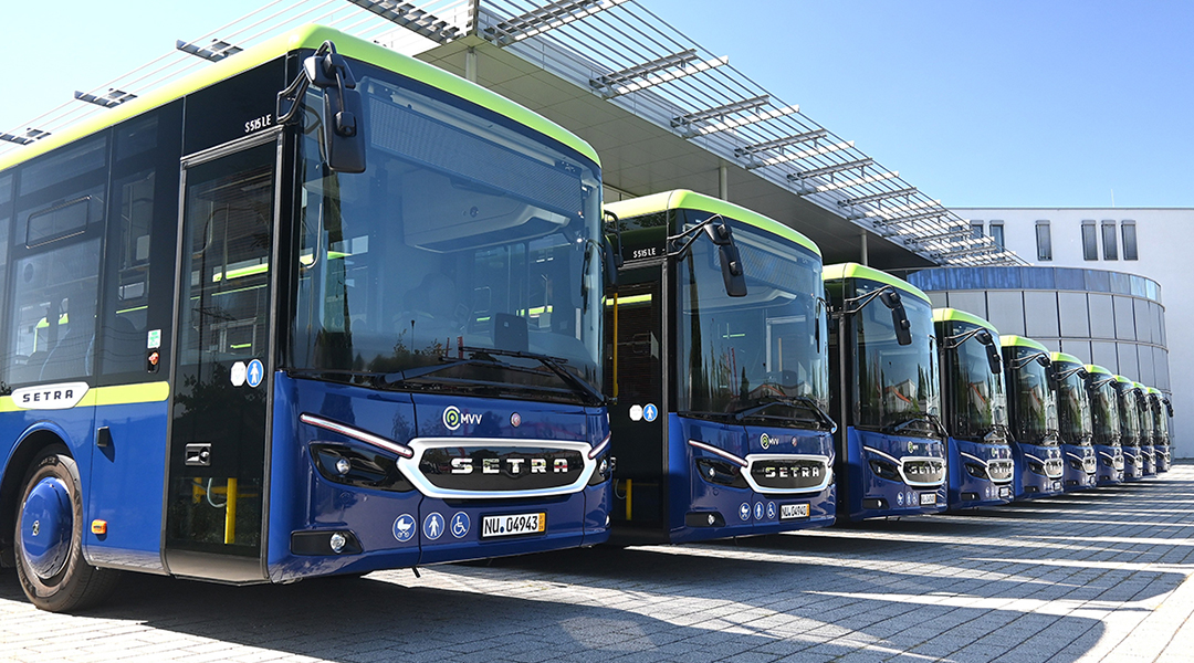 Zehn Überlandbusse stehen vor einer Halle.