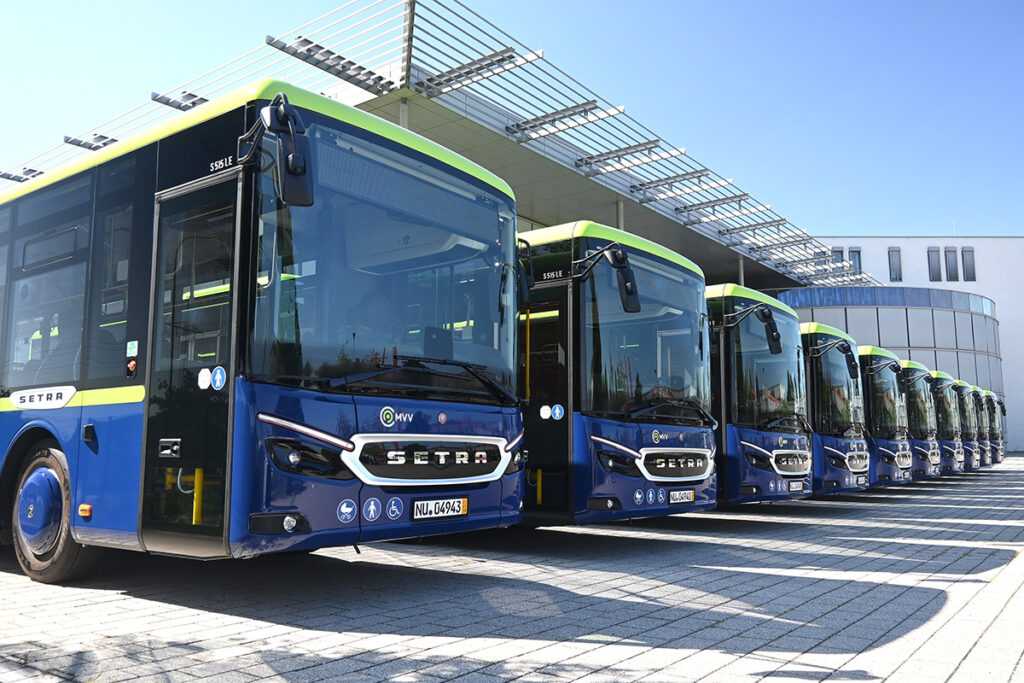 Zehn Überlandbusse stehen vor einer Halle.