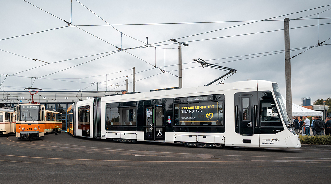 Eine Straßenbahn steht neben anderen Bahnen vor einer Halle.