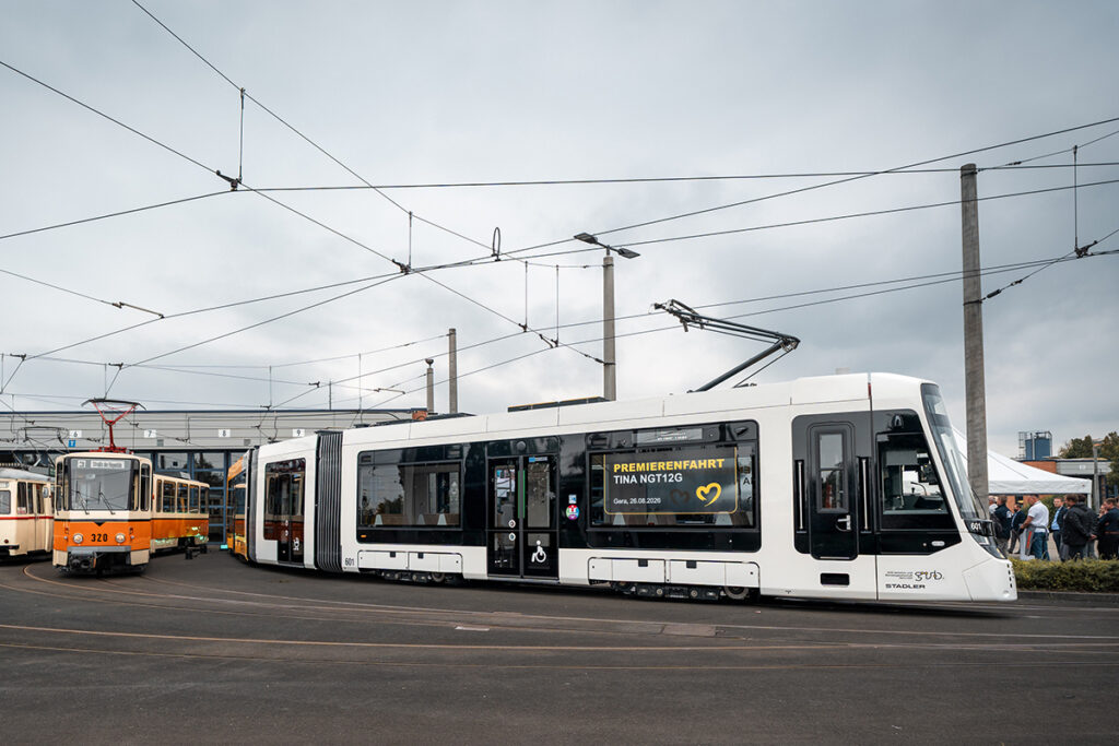 Eine Straßenbahn steht neben anderen Bahnen vor einer Halle.