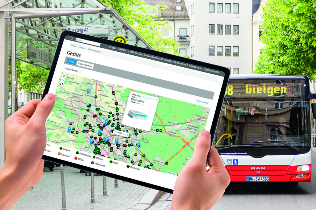Ein Tablet mit einer Karte wird vor einem Bus im Hintergrund gehalten.
