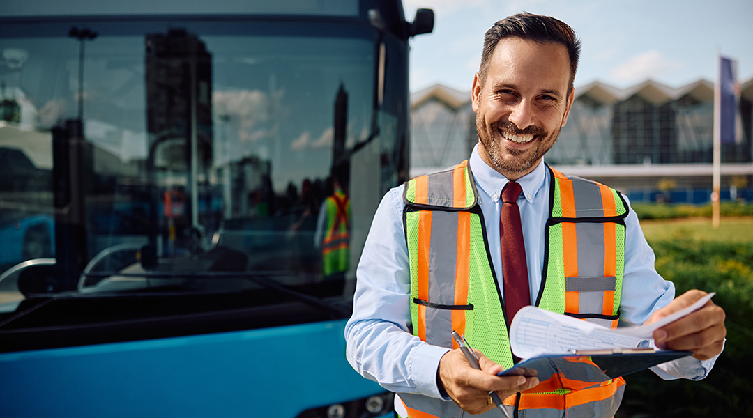 Eine Person in einer Warnweste steht vor einem Bus.
