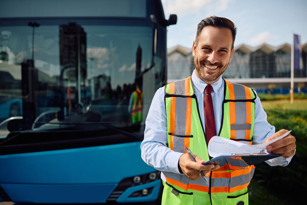 Eine Person in einer Warnweste steht vor einem Bus.