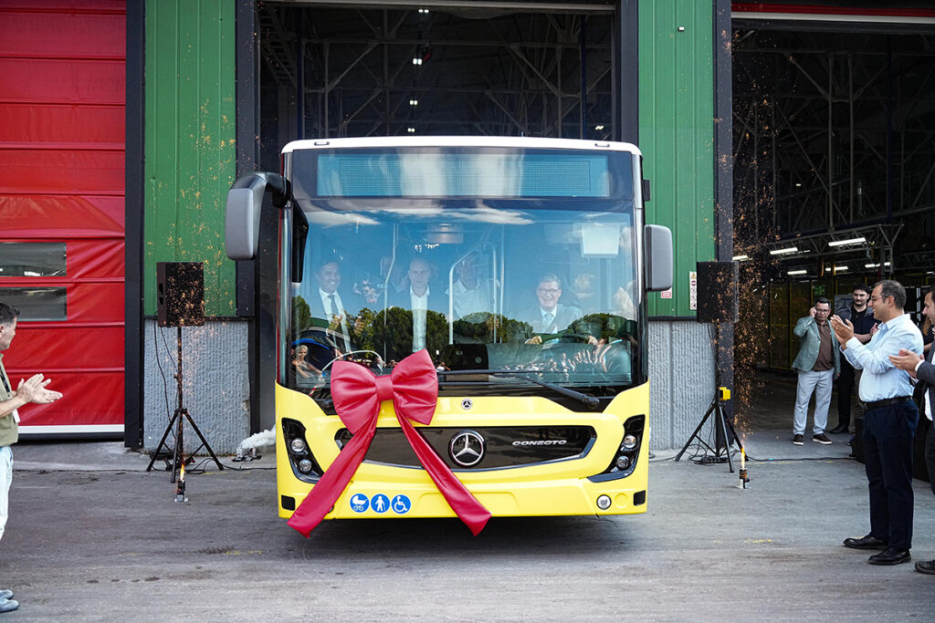 Ein Bus fährt aus einer Halle, Personen applaudieren.