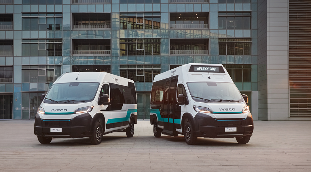 Zwei Minibusse stehen nebeneinander vor einem mehrstöckigen Haus.
