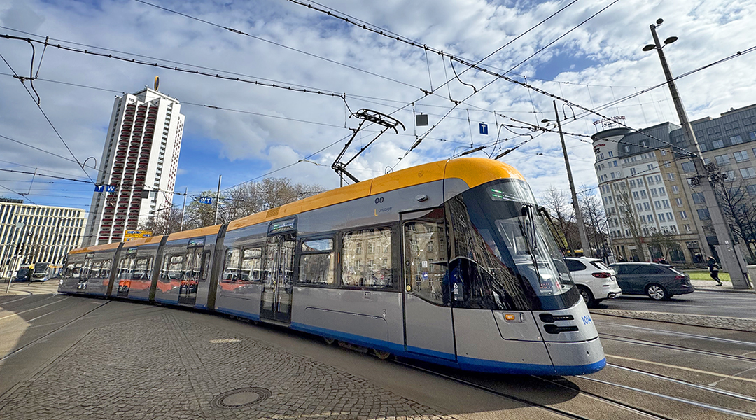 Eine Straßenbahn fährt vor Häusern entlang.