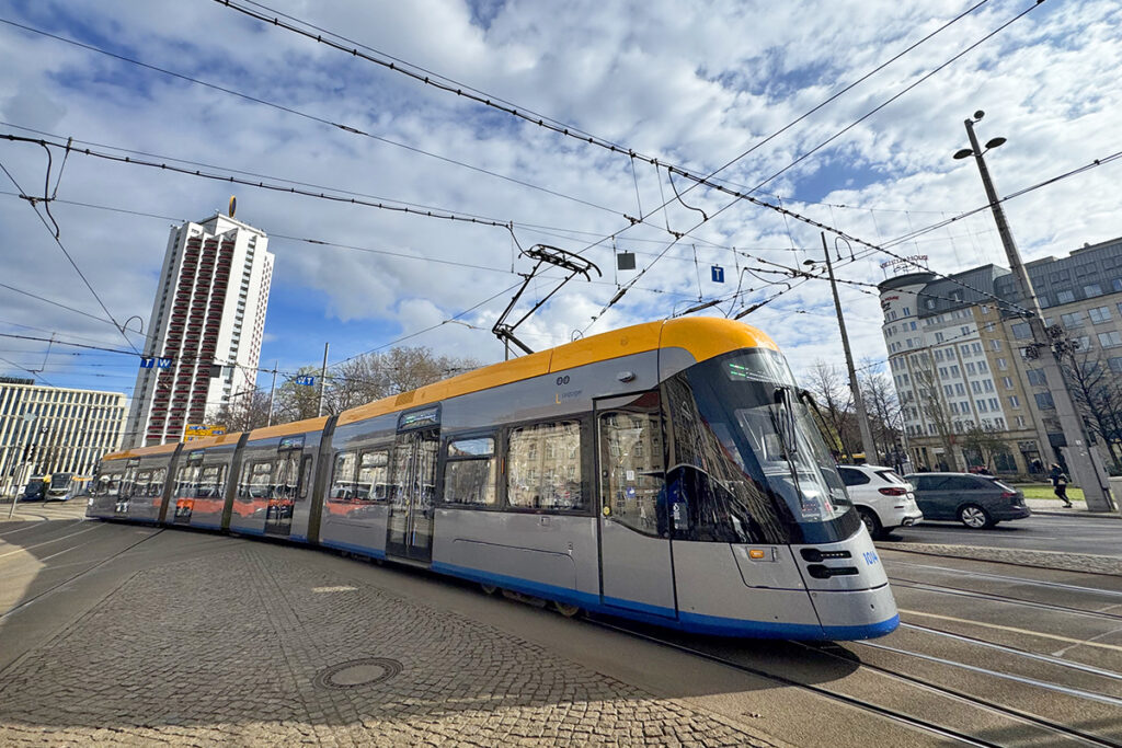 Eine Straßenbahn fährt vor Häusern entlang.