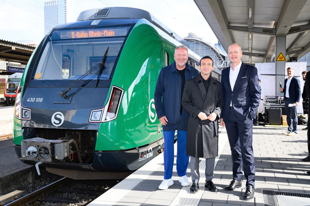 Mehrere Personen stehen neben einem S-Bahn-Zug auf dem Bahnsteig.