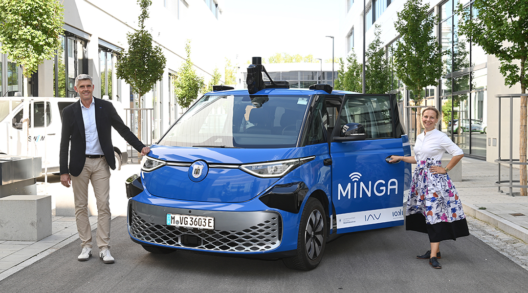 Zwei Personen stehen neben einem autonomen Fahrzeug.