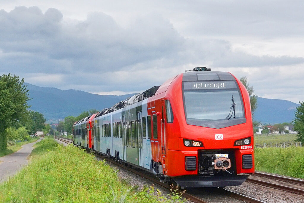 Ein Zug fährt durch Wiesen und Wälder.