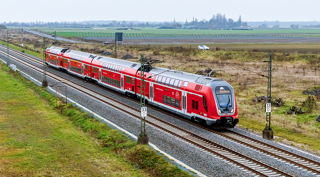 Ein Triebzug fährt auf einer zweigleisigen Strecke.