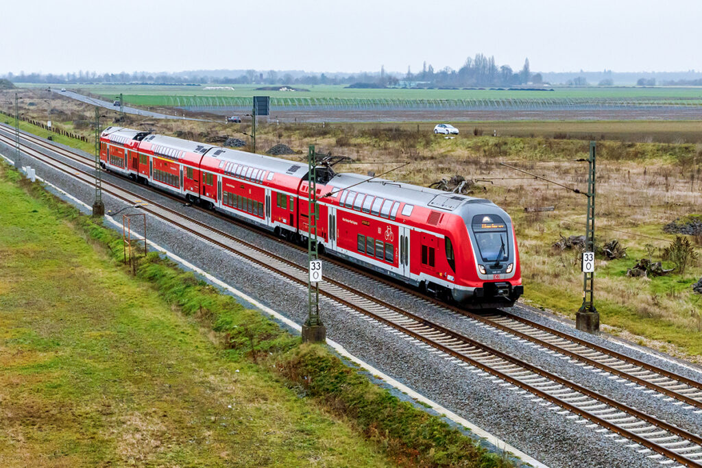Ein Triebzug fährt auf einer zweigleisigen Strecke.