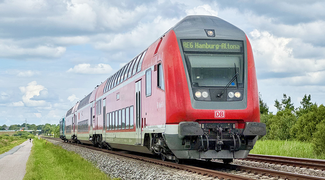Ein Doppelstockzug fährt auf einer zweigleisigen Bahnstrecke.