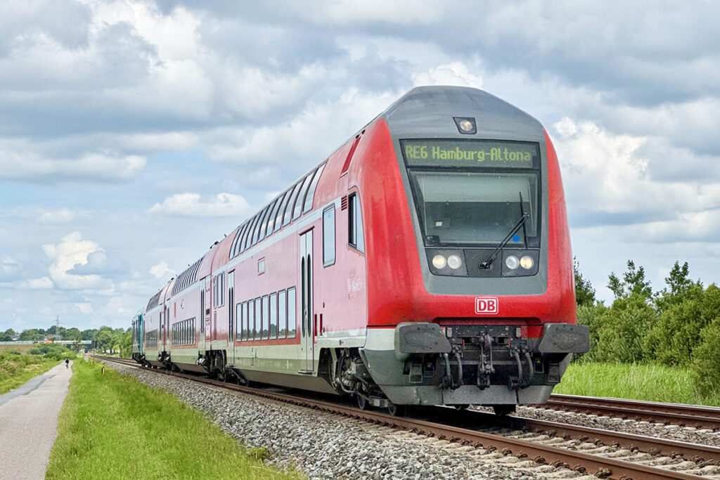 Ein Doppelstockzug fährt auf einer zweigleisigen Bahnstrecke.