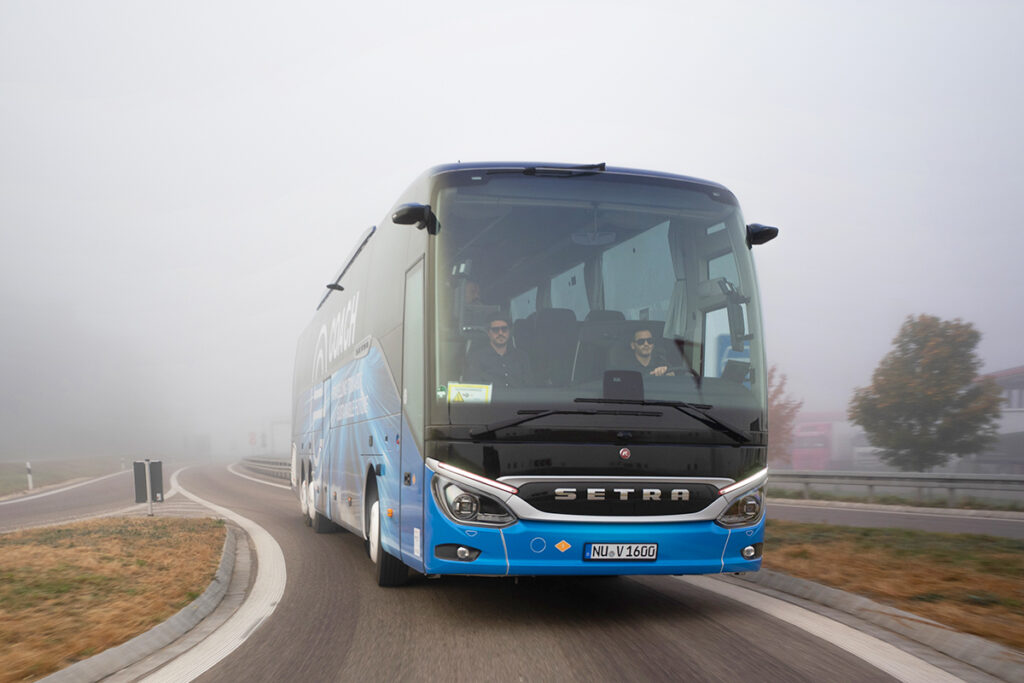 Ein elektrischer Reisebus fährt auf einer Straße.