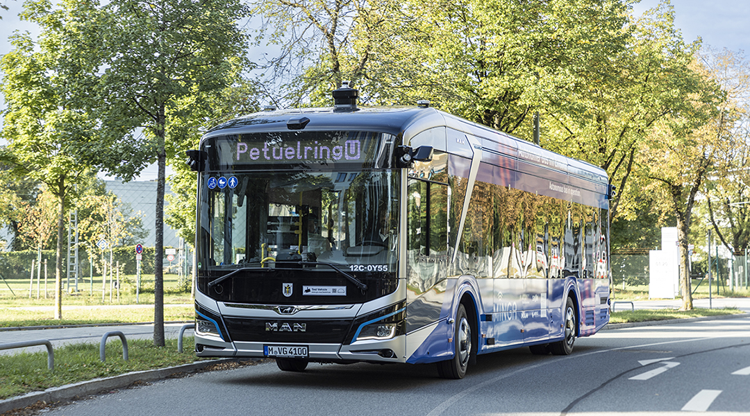 Ein mit Sensoren ausgestatteter Bus fährt auf einer Straße unter Bäumen.