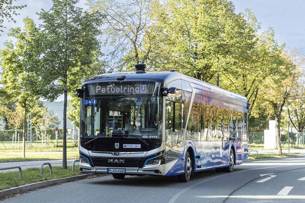 Ein mit Sensoren ausgestatteter Bus fährt auf einer Straße unter Bäumen.