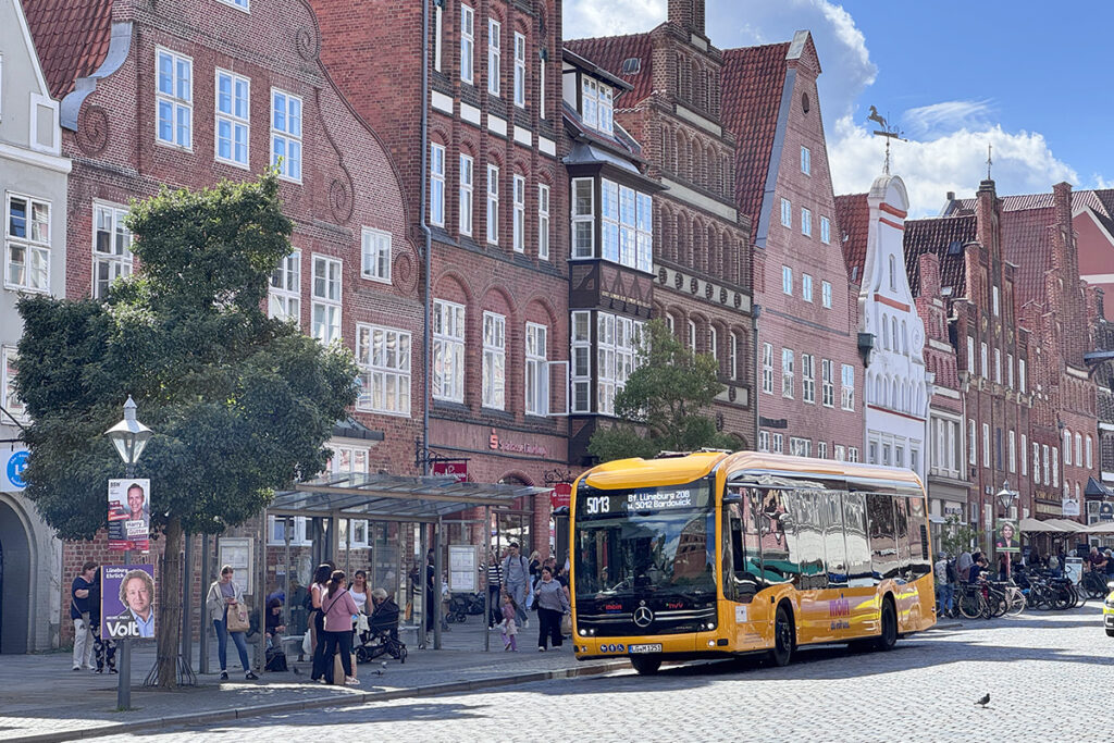 Ein Elektrobus steht vor Häusern mit historischen Fassaden.