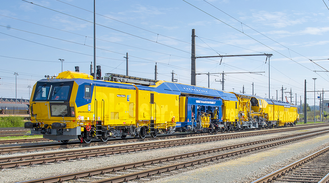 Eine lange Gleisbaumaschine steht auf einem Gleis.