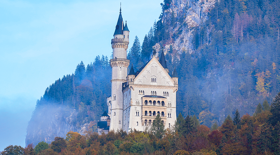 Blick auf Schloss Neuschwanstein mit einer Felswand im Hintergrund.